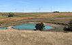 Farm pond with low water level due to drought conditions.